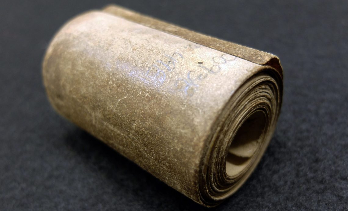 Das Bild zeigt Amulett aus dem 17. Jh., welches aussieht wie eine fein säuberlich zusammengerollte Schriftrolle.
