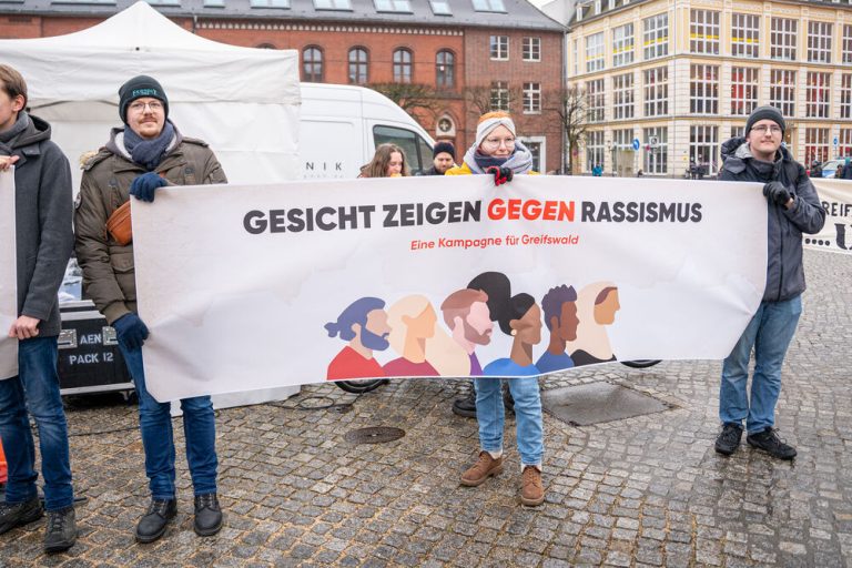 Drei Personen halten während der Demonstration ein Banner mit dem Motiv der Kampagne.
