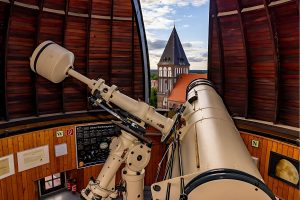 Das Teleskop der Sternwarte zeigt durch das geöffnete Kuppeldach auf den Dom von Greifswald