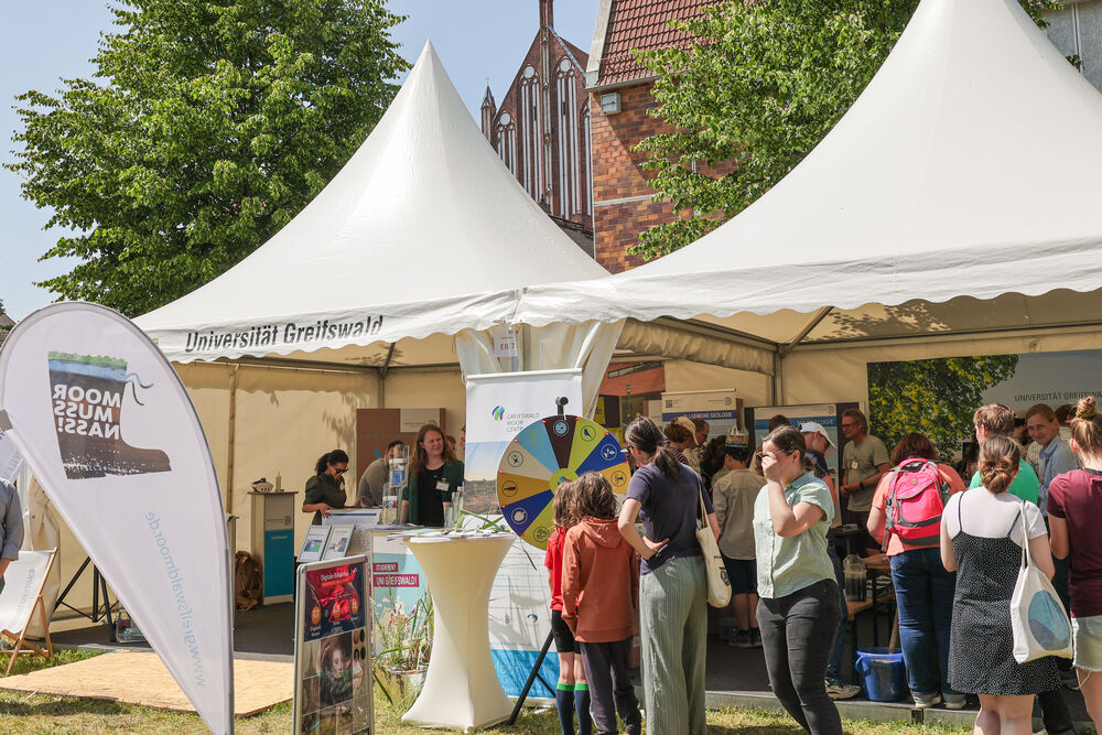 Menschen stehen vor und im Pavillon der Universität Greifswald.