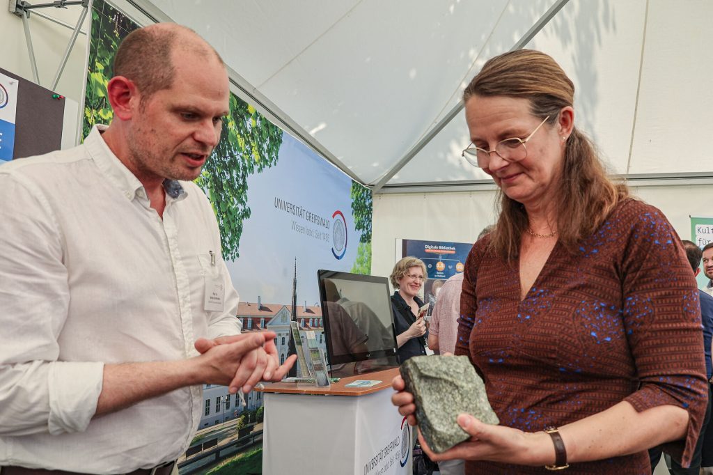 Prof. Dr. Armin Dielforder von der Arbeitsgruppe Allgemeine Geologie zeigt Wissenschaftsministerin Bettina Martin Gesteine.