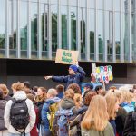 Die Tutor*innen begrüßen die neuen Erstis am Beitz-Platz vor der Mensa in der Erstiwoche. Sie haben Schilder dabei.