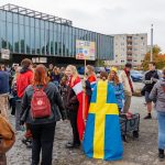 Tutor*innen stehen mit ihren Schildern und sogar Flaggen von Schweden und Dänemark vor der Mensa, um die neuen Erstis abzuholen