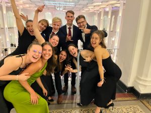 Die Teilnehmer*innen beim Bankett-Abend. Sie haben Abendkleidung an und haben Spaß auf dem Bild