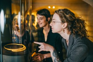 Zwei Frauen schauen sich Schmuck aus Wikingerzeiten in einem Museum an.