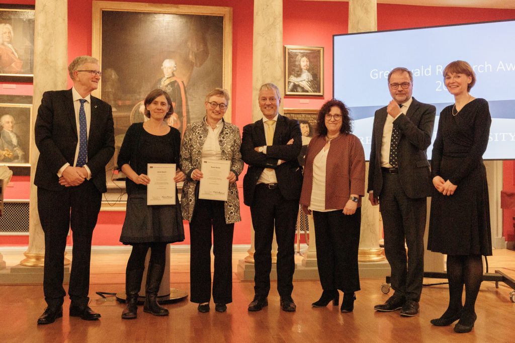 Preisverleihung, die Preisträger stehen mit weiteren Personen in Reihe vor einer Wand