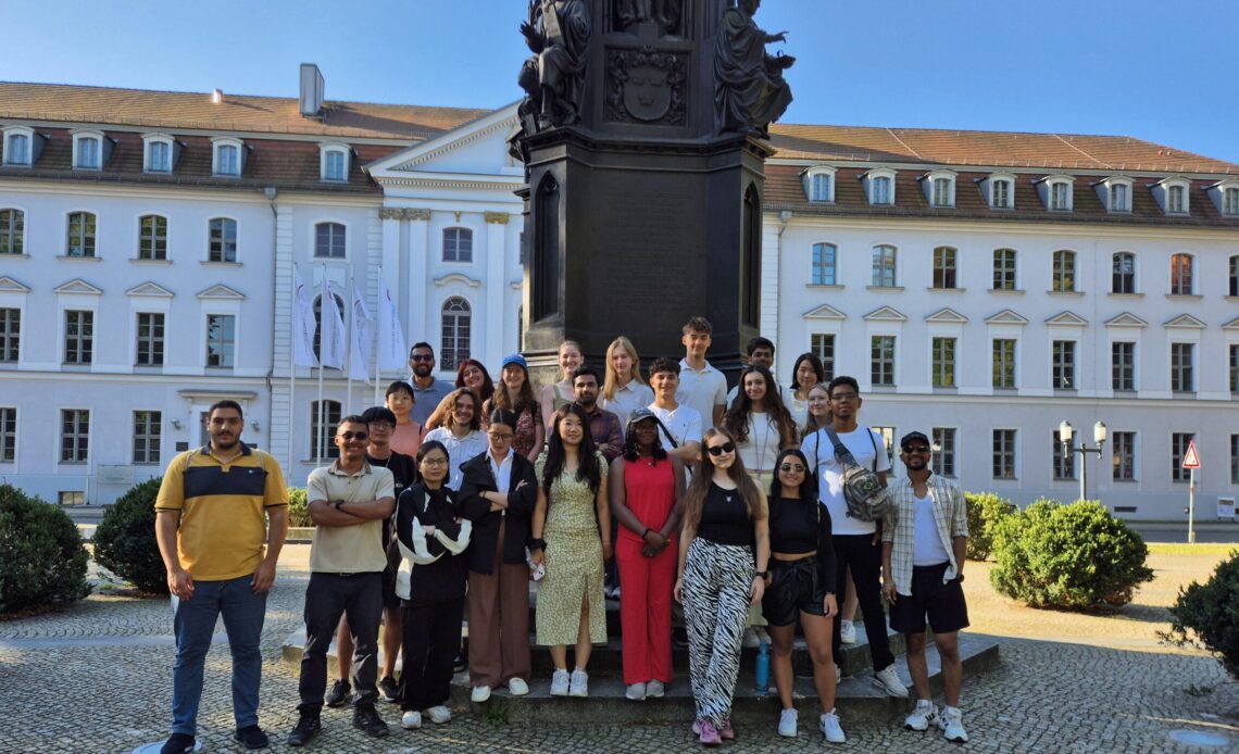 Gruppenbild der Sustain MV Sommerschule, zahlreiche Menschen stehen vor einem Denkmal