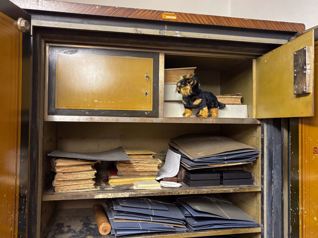 Ein Holzschrank gefüllt mit Papieren, Ordnern und einer kleinen Spielzeugtierstatue.