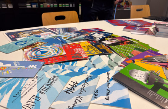 Viele bunte Flyer von Nordischen Klang liegen auf einem Tisch verteilt.