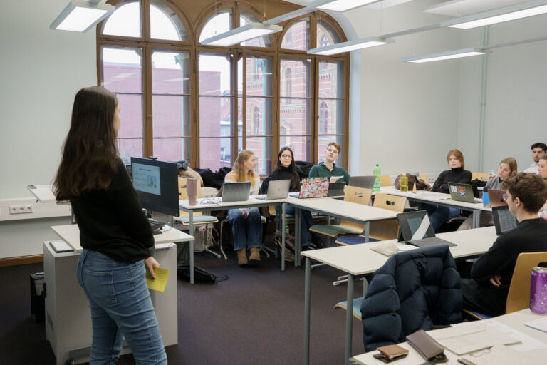 Eine Gruppe von Studierenden sitzt in einem hell erleuchteten Klassenraum und arbeitet gemeinsam an ihren Laptops.