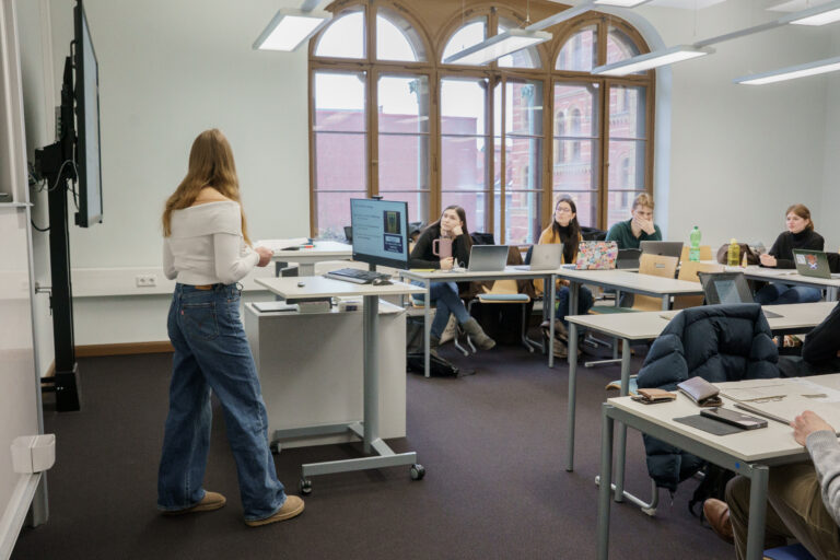 Eine Gruppe von Personen arbeitet in einem modernen Büroraum mit großen Fenstern.