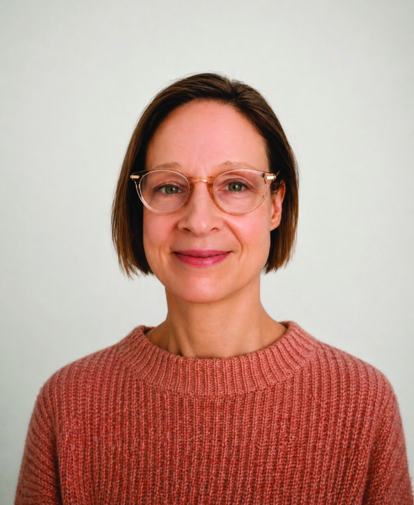 Eine Frau mit Brille und mittelkurzen braunen Haaren lächelt in die Kamera.
