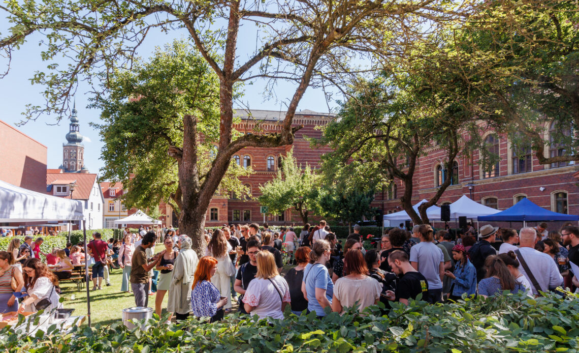 Menschen feiern auf einem Campus ein Hoffest bei bestem Wetter