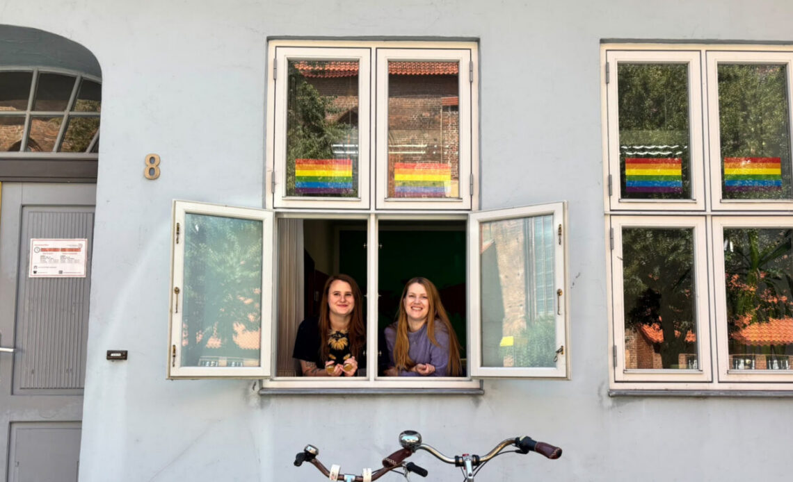 Zwei frauen gucken aus einem Fenster.