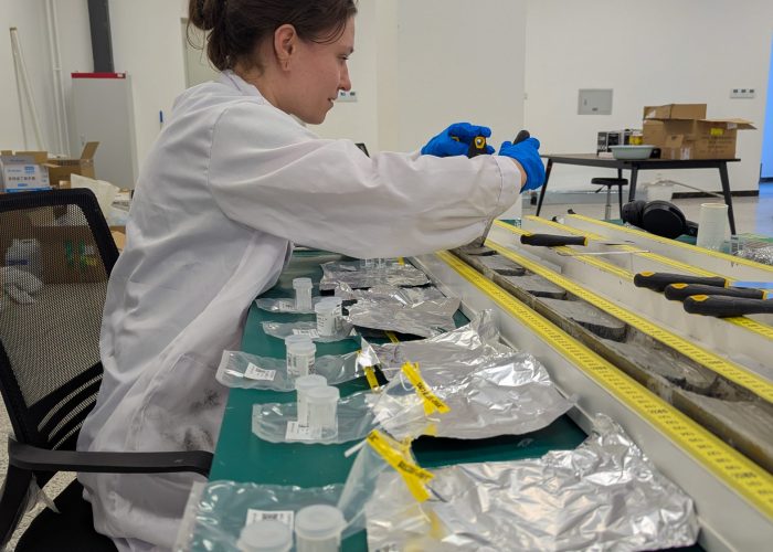 Eine Frau in einem Laborkittel untersucht die Sedimente im Labor. Foto: Marie-Luise Adolph