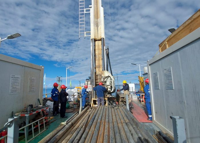 Eine Gruppe von Menschen steht um eine große Bohranlage herum.